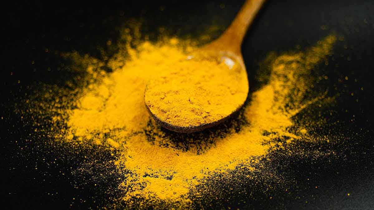 Turmeric Powder on a Spoon Black Background