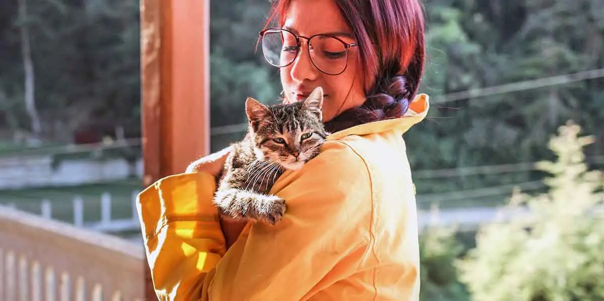 woman snuggling cat on porch